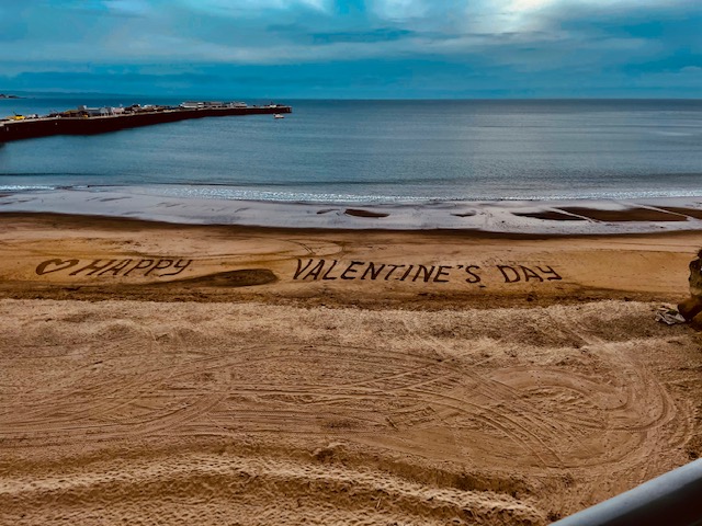 Beach with Happy Valentine's Day written in the sand