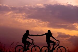 Man and woman holding hands on bicycle